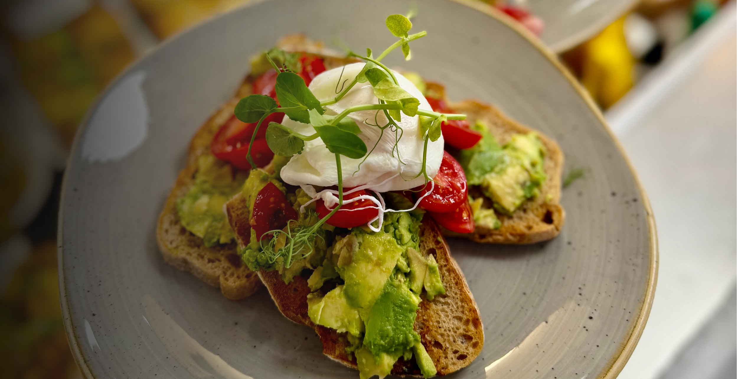 Smashed avocado on sourdough toast with fresh tomatoes and a poached egg