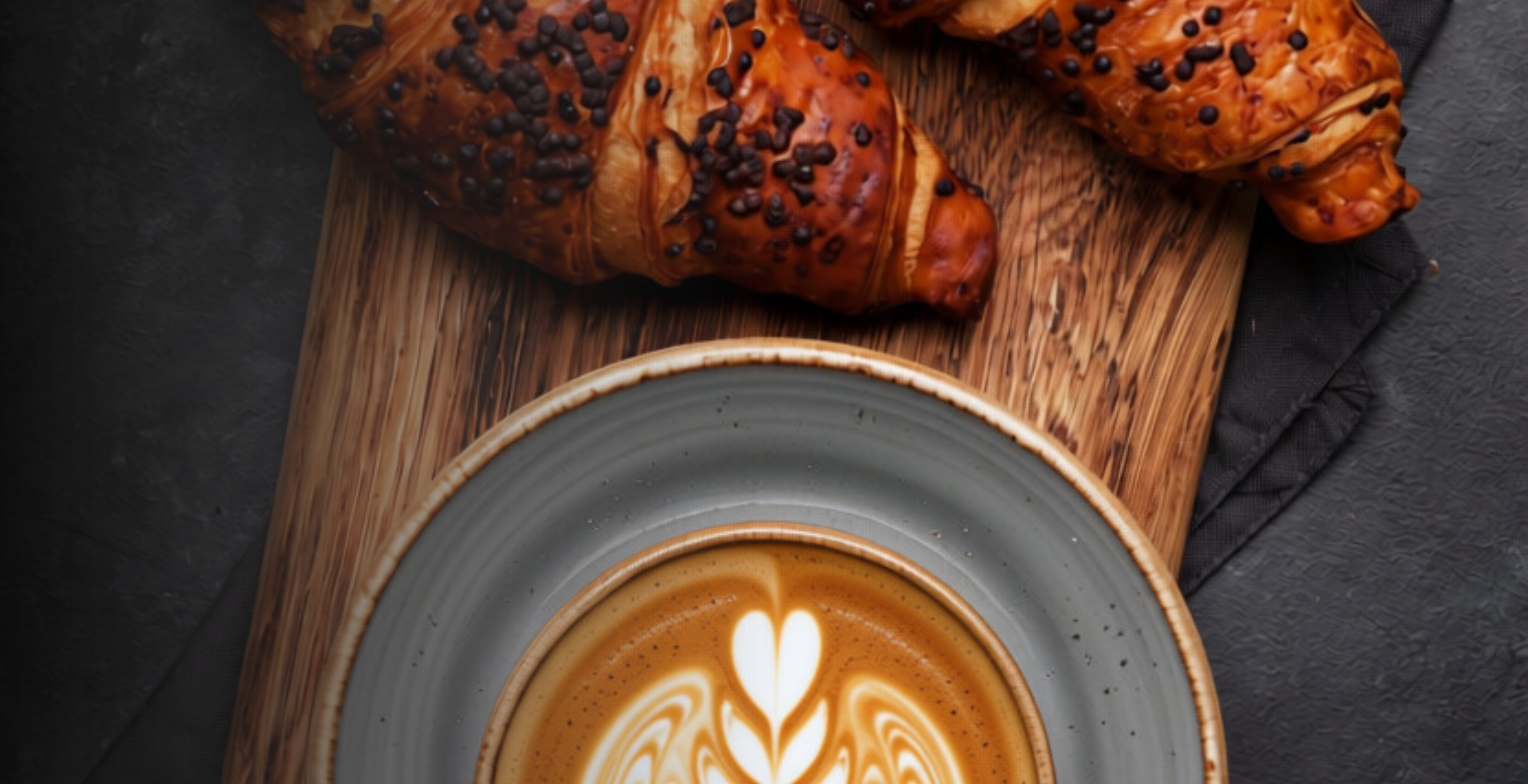 Chocolate croissants and a latte on wooden board